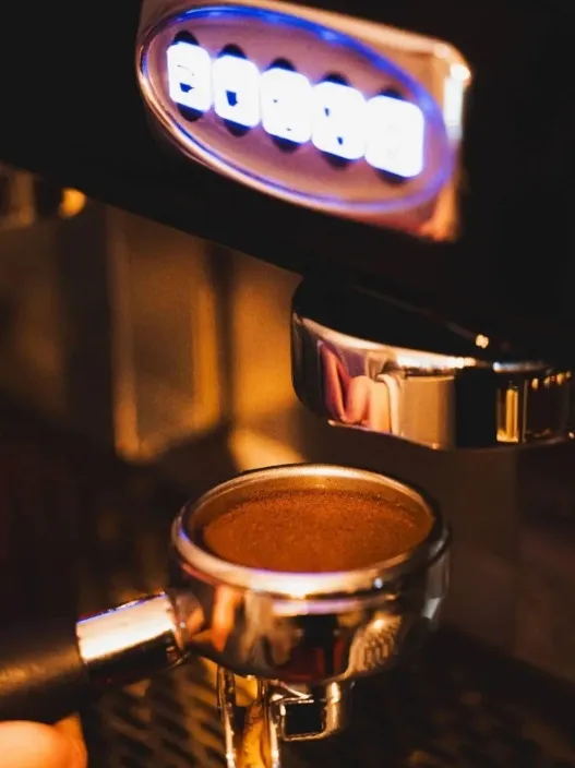 Portafiltro con café listo bajo la máquina de espresso